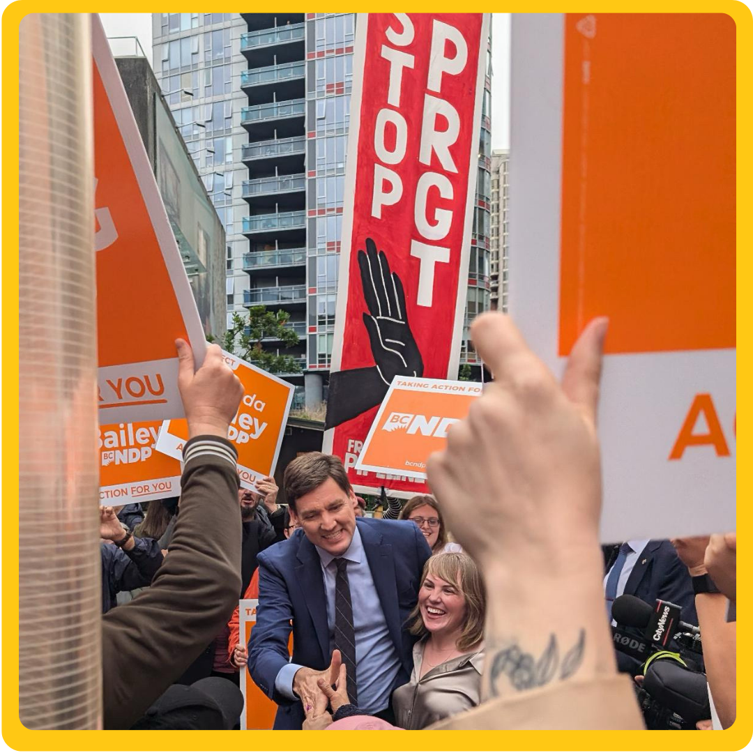 a man and woman smiling in the middle of a stop PRGT rally. end of image description.