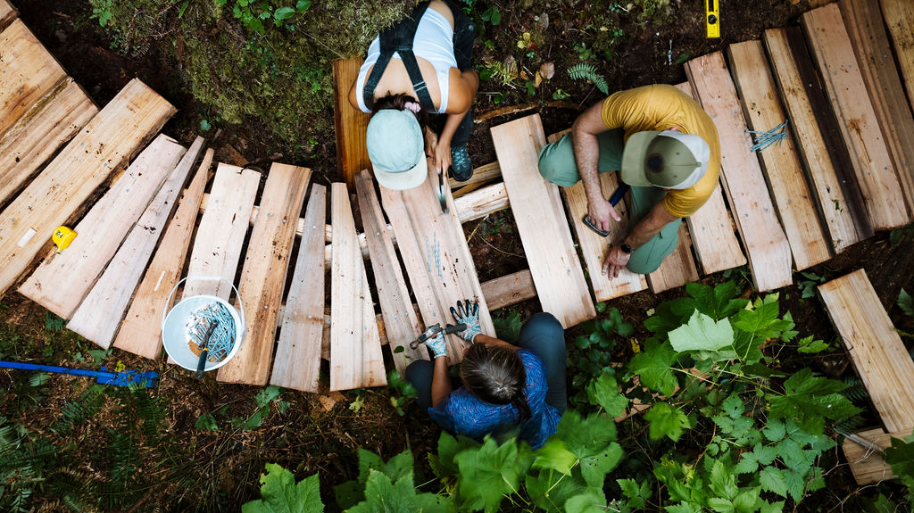 An aerial view of three people building a boardwalk. end of image description.