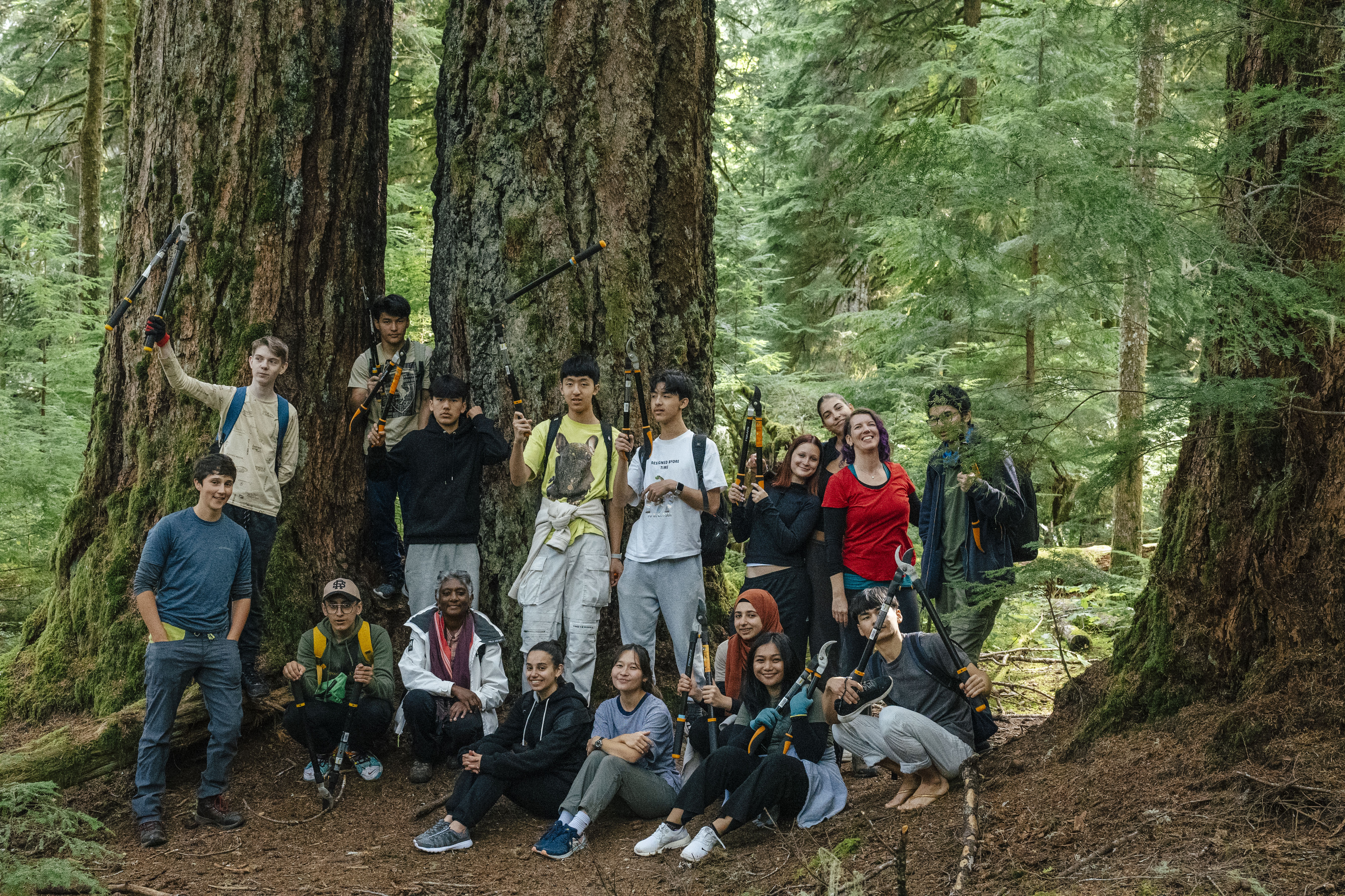 A group of youth with trail building tools in a forests. end of image description.