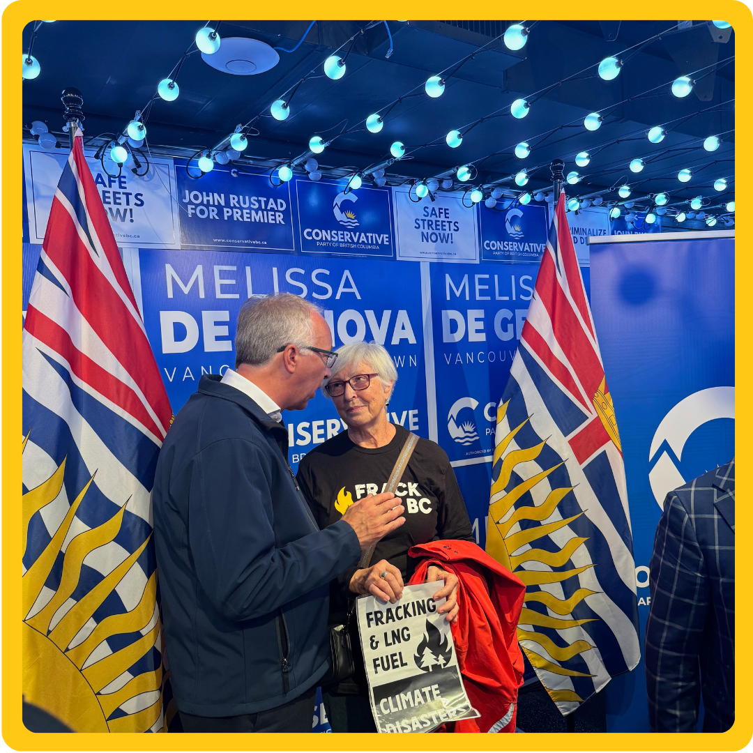 Two people talking with an anti fracking placard in hand. end of image description.