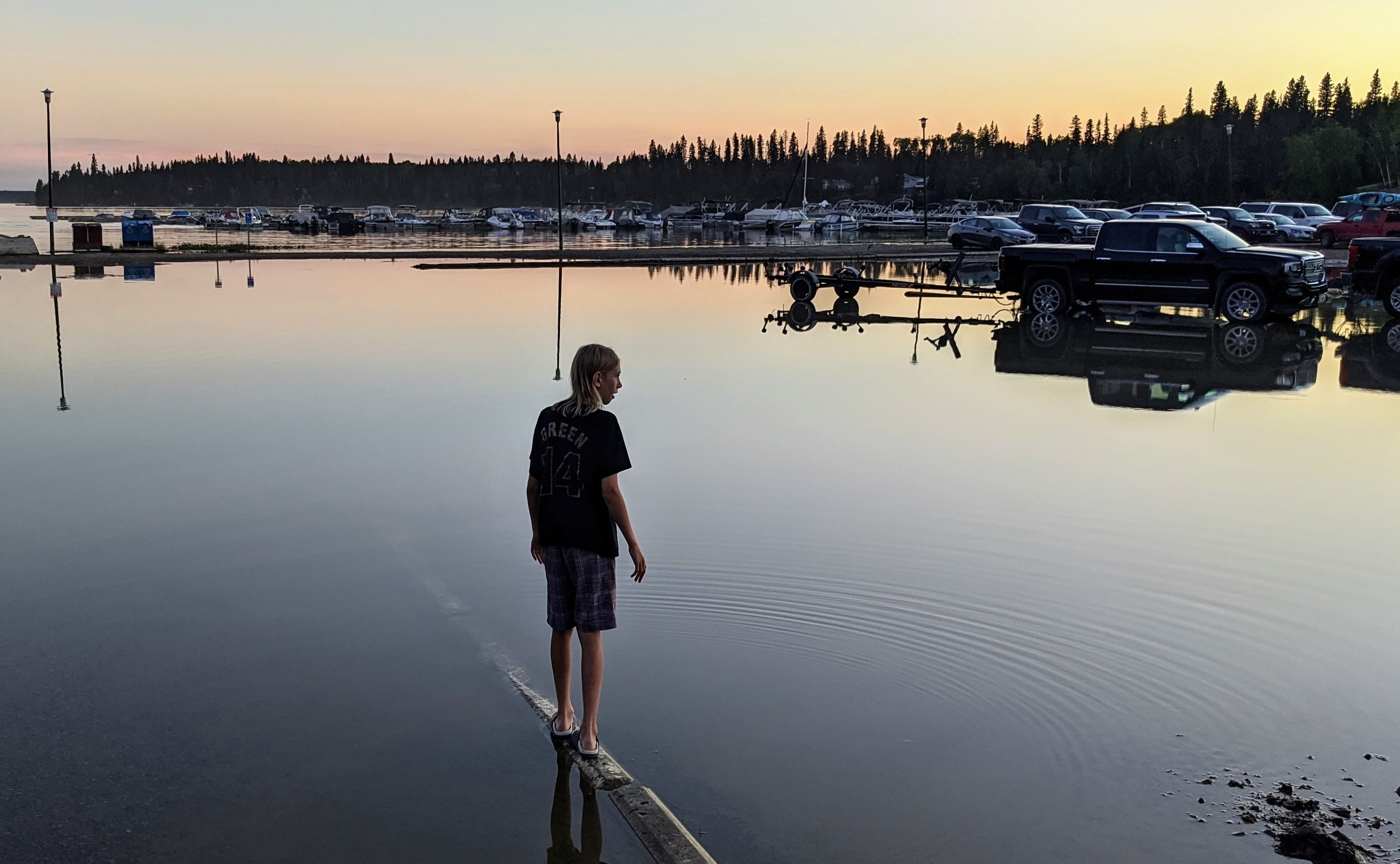 A young boy balances in the shallows of a flood in Paint Lake Provincial Park