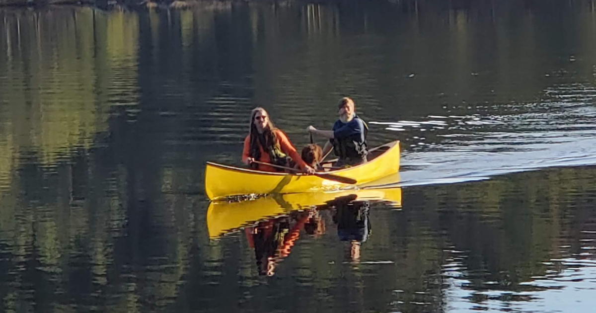 Two people with a dog in a canoe. End of image description.