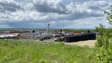 A fracked gas drill site set in a beautiful landscape. End of image description.