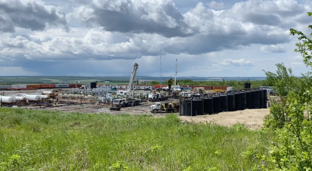 A fracked gas drill site set in a beautiful landscape. End of image description.